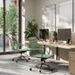 Modern office setup with green chairs, desks, and computer monitors.
