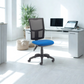 Blue office chair in a bright room with a desk and computer setup.