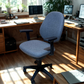 Blue office chair in a home office setting with desks and computers.