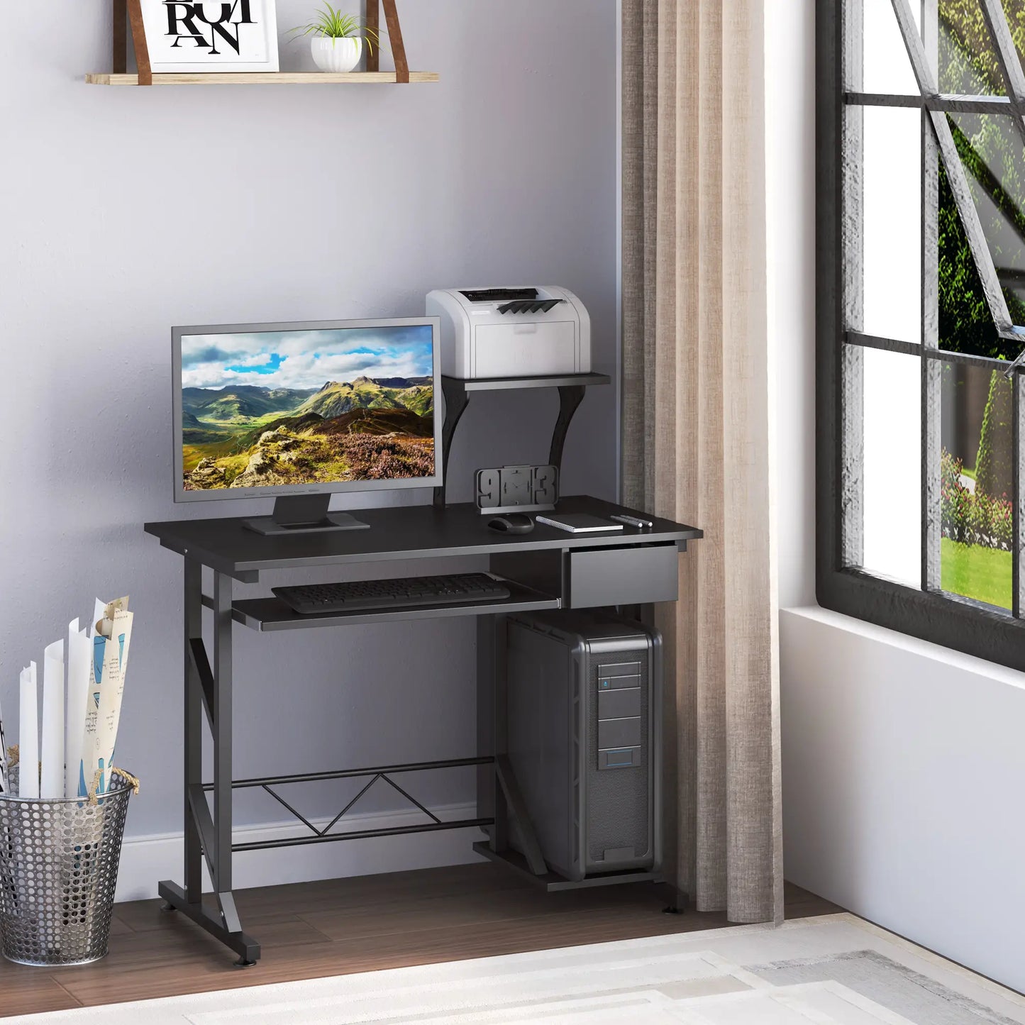A black computer desk with a monitor, keyboard, and a notebook placed on it. The desk has a sliding keyboard tray, a drawer, and a CPU stand.