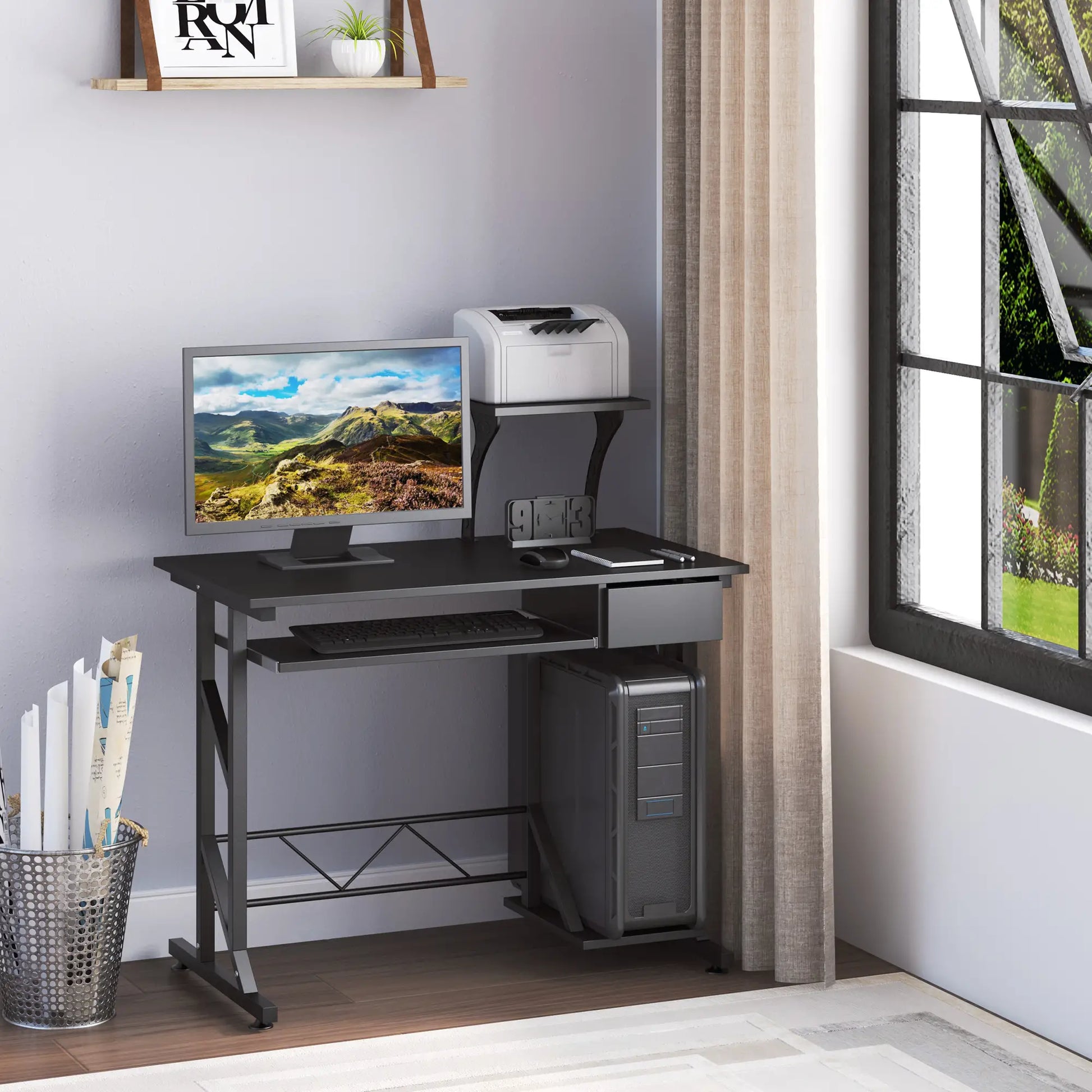 A black computer desk with a monitor, keyboard, and a notebook placed on it. The desk has a sliding keyboard tray, a drawer, and a CPU stand.
