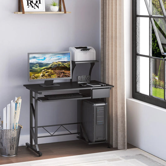 A black computer desk with a monitor, keyboard, and a notebook placed on it. The desk has a sliding keyboard tray, a drawer, and a CPU stand.
