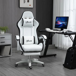 A white and black computer gaming chair with footrest, positioned in a room with a desk and computer setup in the background.