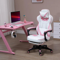A pink and white computer gaming chair with lumbar support and footrest, positioned in a room with a pink desk and a computer setup.