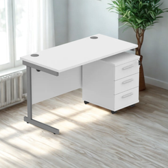 White office desk with three drawers in a bright room with a plant.