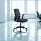 Black office chair in a modern office setting with large windows.
