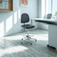 Black office chair in a bright office setting with a desk and laptop.
