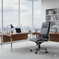 Modern office desk with a laptop, lamp, and chair in front of large windows with a cityscape view.