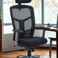 Black office chair with mesh back in a room with large windows.