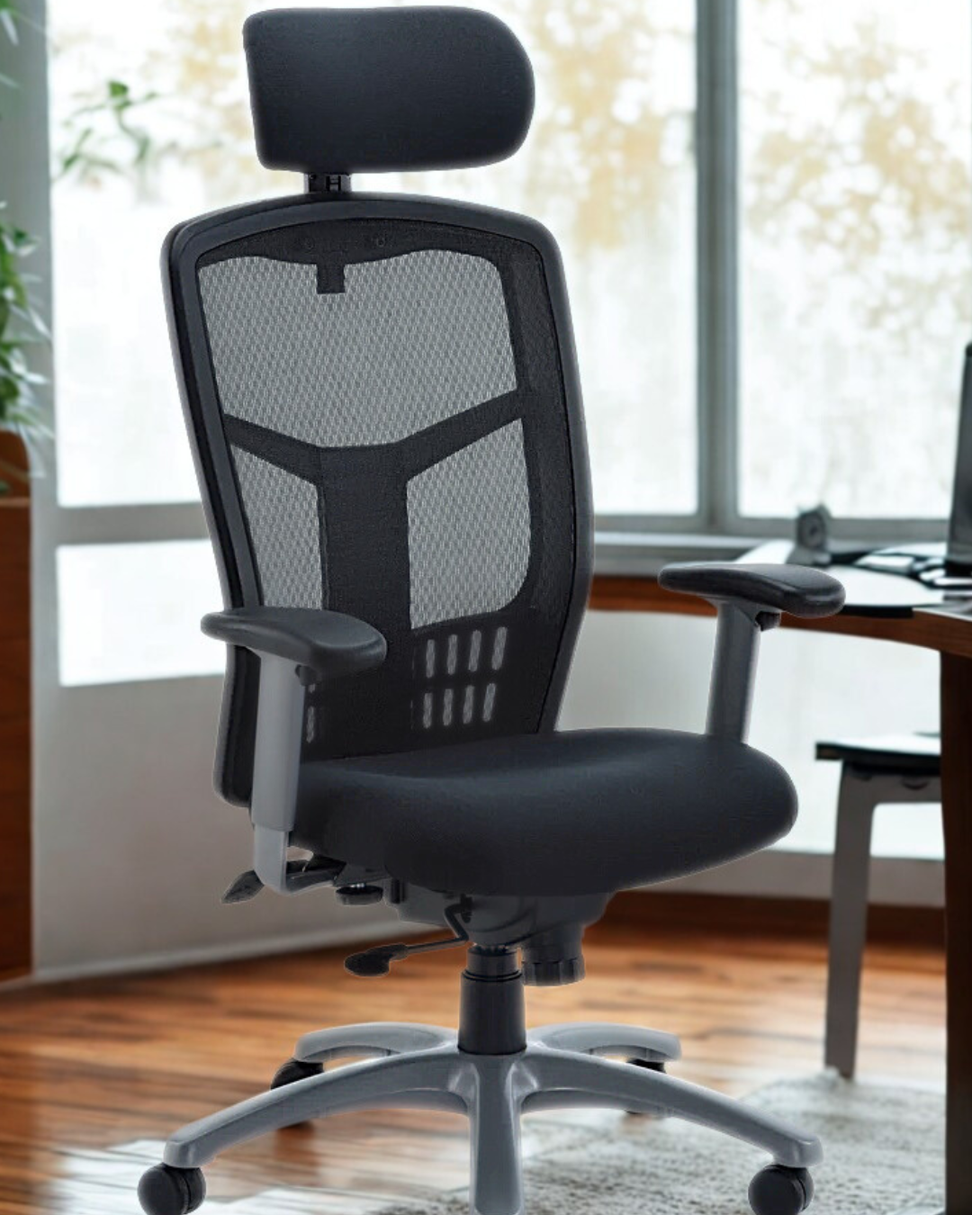 Black office chair with mesh back in a room with large windows.