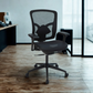 Black office chair in an office setting with a desk and window in the background.