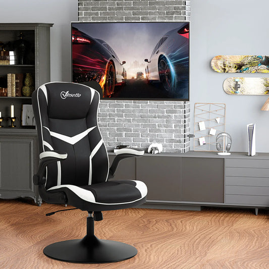 A black and white gaming chair with thick padding and flip-up armrests, placed in a room with a flat-screen TV and gaming console in the background.