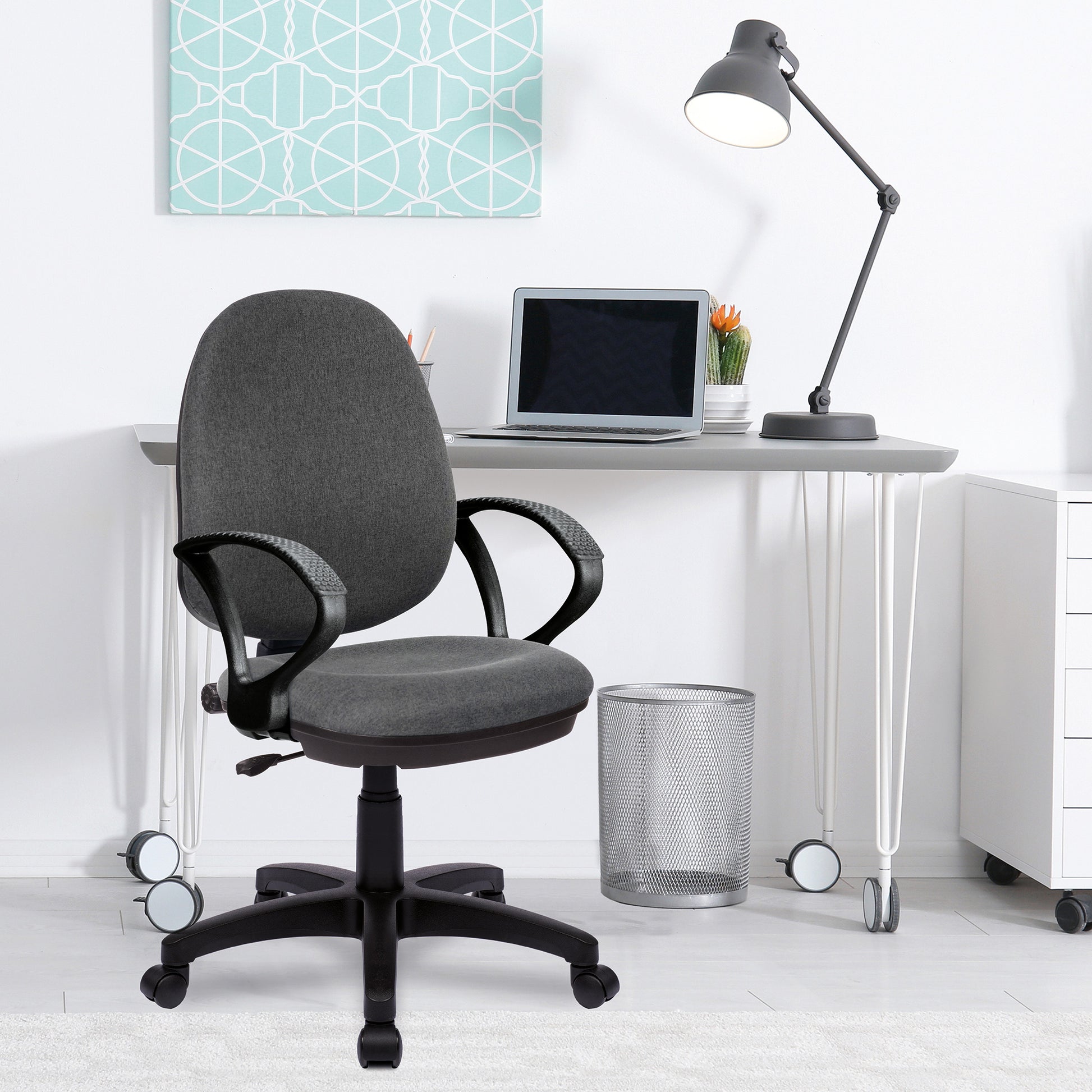 Gray office chair in front of a white desk with a laptop and lamp.