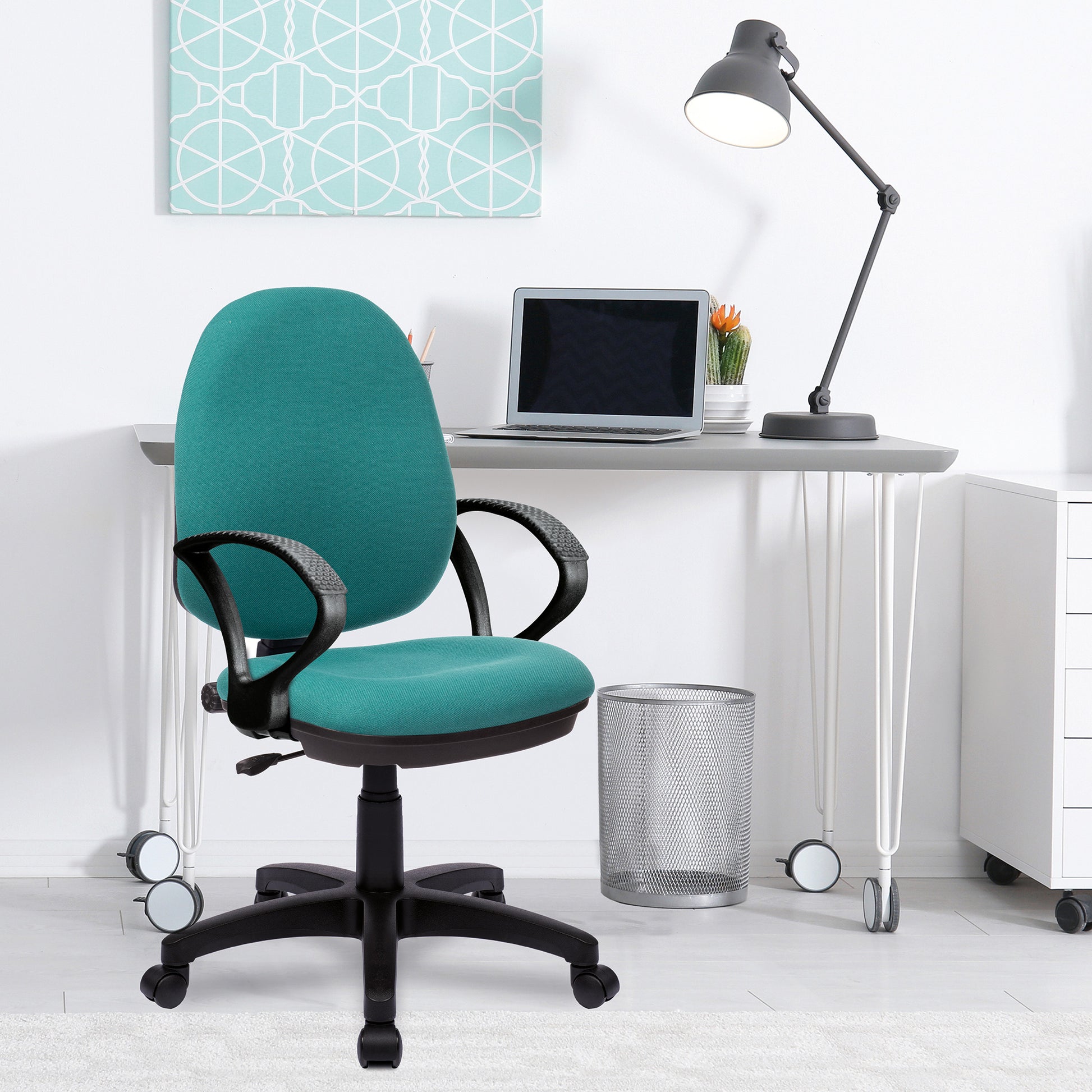 Teal office chair in front of a white desk with a laptop and lamp.