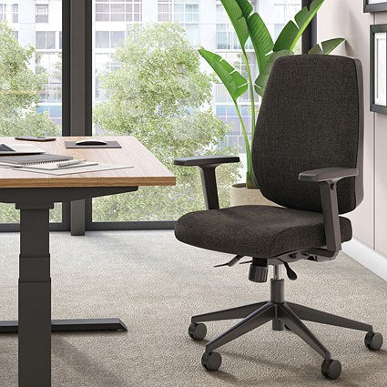 Black office chair in an office setting with a desk and large windows.