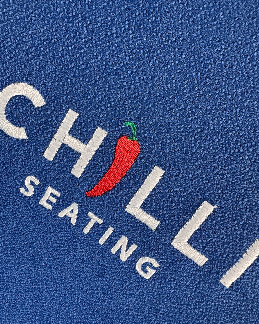Embroidered logo on blue fabric with 'CHILLI SEATING' text and red chili pepper.