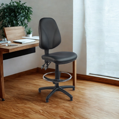 Black office chair in front of a wooden desk with a plant and window in the background.