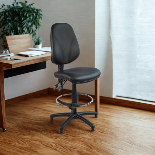 Black office chair in front of a wooden desk with a plant and window in the background.
