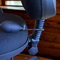 Close-up of a blue office chair with a flexible armrest attachment on a wooden floor.
