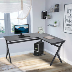 An L-shaped gaming desk with a black MDF tabletop and steel frame, including a CPU stand, set in a room with various decor.