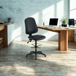 Black office chair in a bright office setting with wooden desks and computers.