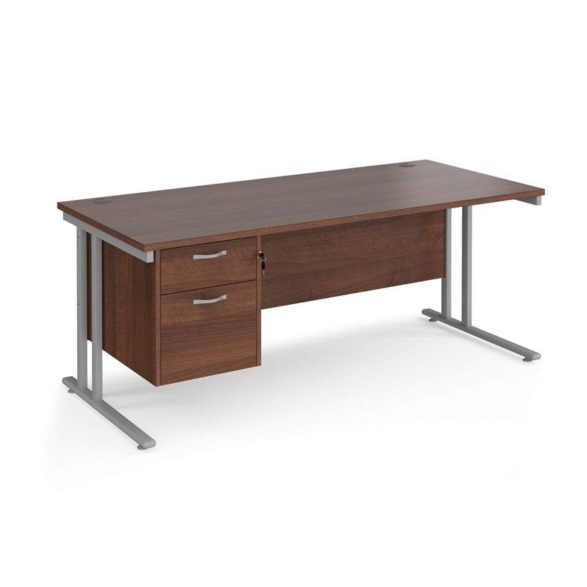 Rectangular office desk with a cantilever frame and a beige two-drawer fixed pedestal. The desk has a melamine finish and is pictured against a white background.
