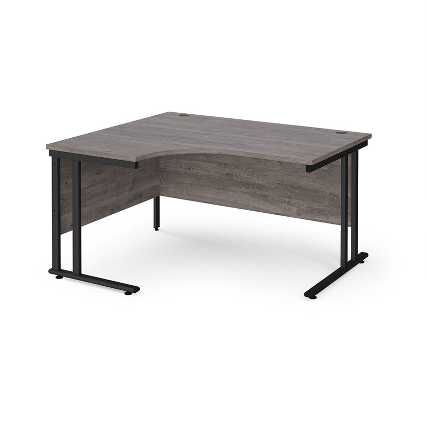 A left hand ergonomic desk with a cantilever frame made of metal and a wooden desktop, positioned against a white background.