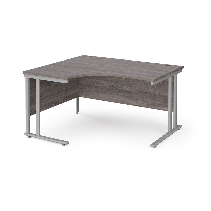 A left hand ergonomic desk with a cantilever frame made of metal and a wooden desktop, positioned against a white background.