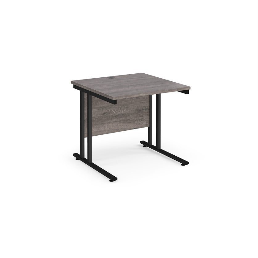 A rectangular office desk with a black cantilever frame and melamine desktop, with one cable access port visible.