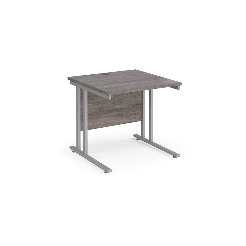 A rectangular office desk with a cantilever frame and melamine desktop, with one cable access port visible.