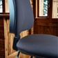 Almost black office chair with adjustable armrests in a room with wooden walls and windows.