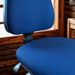 Blue office chair in an indoor setting with wooden walls.