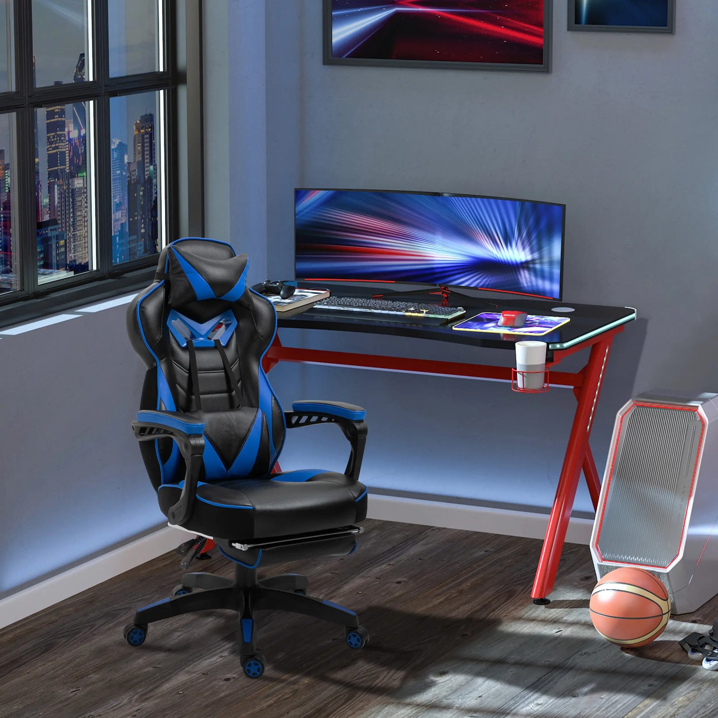 A black and blue gaming chair with thick padding, padded armrests, and a high backrest, situated in a room with a desk and a computer setup in the background.