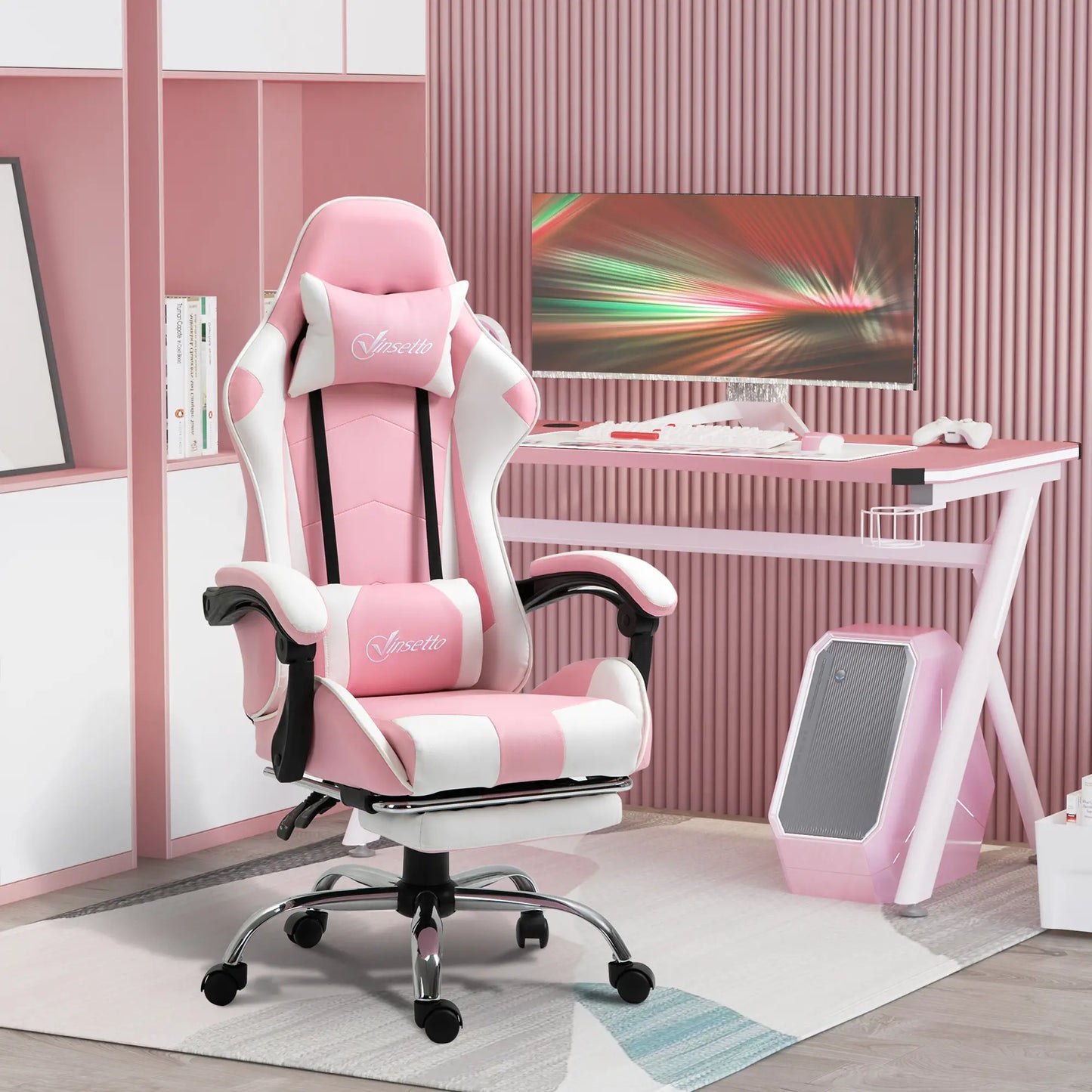 A pink and white computer gaming chair with a 135-degree reclining back and retractable footrest, placed in a room with a desk and a computer setup.