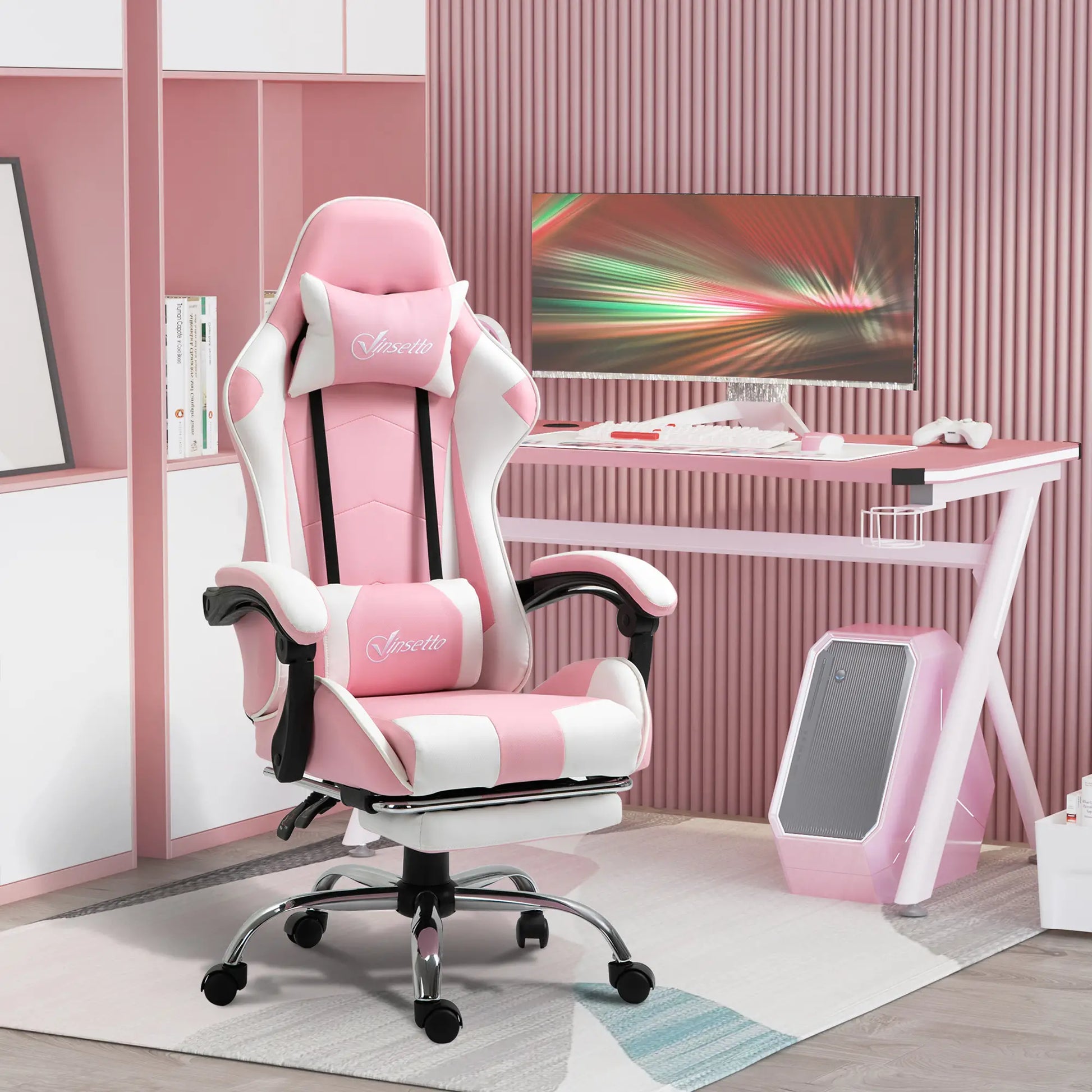 A pink and white computer gaming chair with a 135-degree reclining back and retractable footrest, placed in a room with a desk and a computer setup.