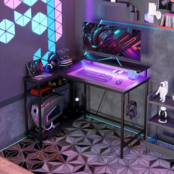 An 'L' shaped gaming/work desk with LED lights in various colors, featuring multiple shelves and a steel frame, set in a room with patterned flooring.