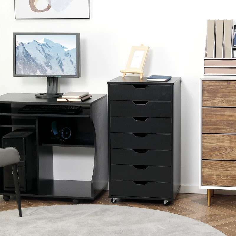 Black office desk with computer setup and a tall black drawer unit in a room.