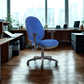 Blue office chair in a modern office setting with large windows.