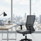 Modern office chair in front of a desk with a cityscape view through large windows.