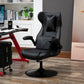 A black video gaming chair with lumbar support, racing style, positioned in a room with a desk and computer setup in the background.