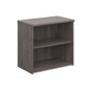 A wooden bookcase with a single opening tambour door and two shelves with a grey finish. 