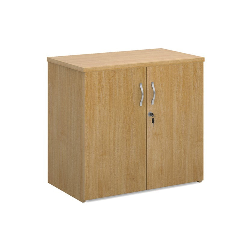 A wooden cupboard with oak finish, featuring a pair of lockable doors with silver handles and a solid back panel.