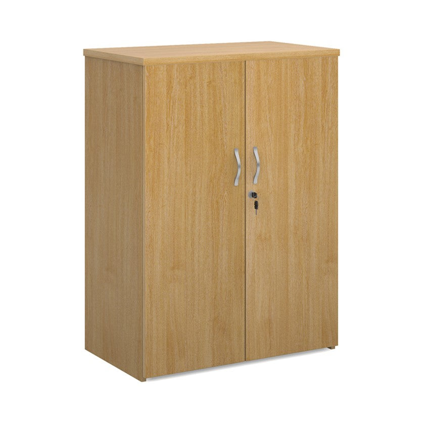 A wooden cupboard with oak finish, featuring a pair of lockable doors with silver handles and a solid back panel.