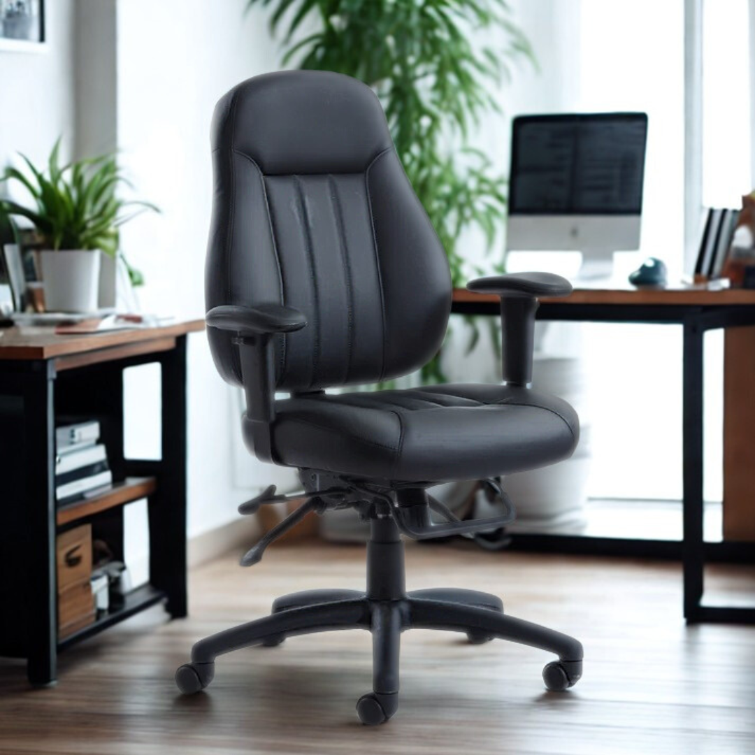 Black office chair in an office setting with a desk and computer in the background.